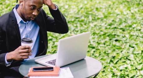 man scratching his head at a laptop